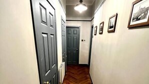 A hallway with wooden flooring, a ceiling fan, and framed pictures on the walls.