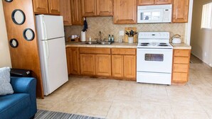 A kitchen with wooden cabinets, a white refrigerator, a stove, and a microwave. - The PB Spot 1BR w/ Parking (San Diego)
