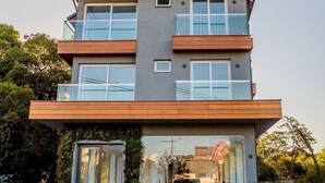 A modern multi-story house with a prominent chimney, large windows, and a well-maintained garden. - LOCAR-IN GRAMADO- HOLLYWOOD (Gramado)