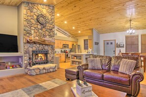 Una sala de estar acogedora con chimenea de piedra, sofá de cuero y televisor.
