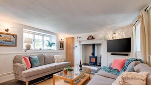 A cozy living room with a sofa set, a coffee table, a fireplace, and a television.