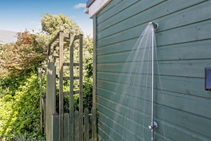 A wooden gate leading to a building with a water spout.