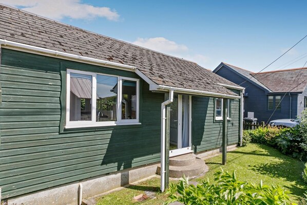 A green single-story house with a front porch, a visible garage, and a well-maintained lawn.