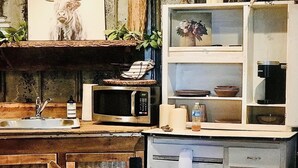 Eine rustikale Küche mit einer Holzausziehtheke, einer Mikrowelle, einem Spülbecken und einem Schrank mit Schubladen.