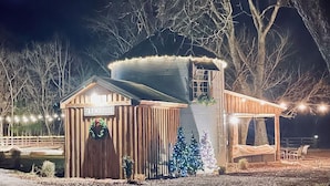 Ein rustikales Bauernhaus mit Holzfassade, einem kleinen Anbau und einem Weihnachtsbaum.