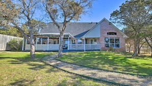 A two-story house with a covered porch and a brick exterior. - Lakefront Getaway w/ Boat Dock, Canoe, Grill! (Granbury)