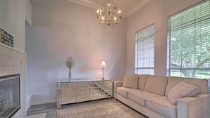 A living room with a beige sofa, a glass coffee table, a chandelier, and a fireplace. - Lakefront Getaway w/ Boat Dock, Canoe, Grill! (Granbury)