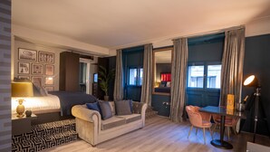 Ett modernt hotellrum med en säng, en soffa, ett matbord och en spegel.