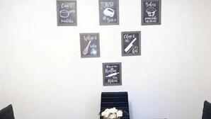 Un coin repas avec une table noire et quatre chaises noires. Cinq panneaux encadrés sont accrochés au mur, chacun portant une phrase différente.