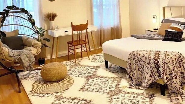 Une chambre à coucher comprenant un lit, un bureau, une chaise, un fauteuil suspendu et un ventilateur de plafond.