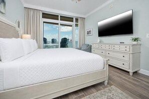 Une chambre avec un grand lit, une commode, un téléviseur et une vue sur l’extérieur.