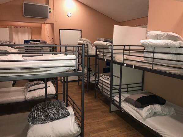 Une chambre de dortoir avec des lits superposés, un téléviseur et un tableau blanc au mur.