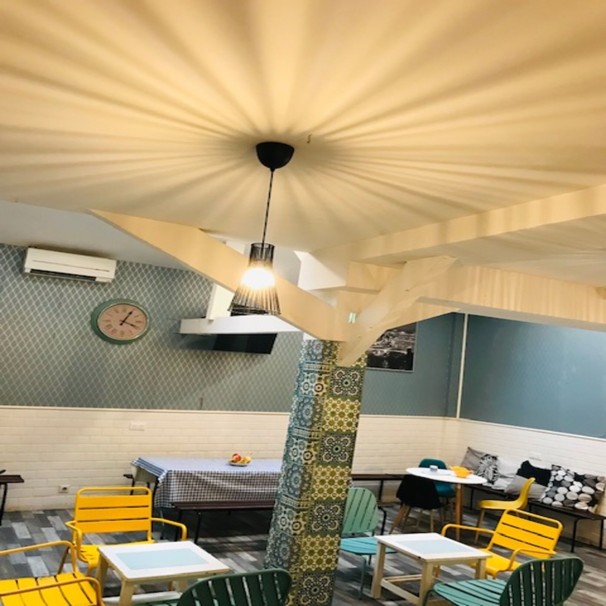 L’intérieur d’un restaurant avec des murs à motifs, une horloge et des chaises jaunes et vertes.