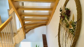 Una escalera de madera con techo de cristal, un adorno en la pared y una planta en maceta.