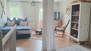 Una habitación amplia con una cama grande, un armario de madera, un televisor y una estantería.