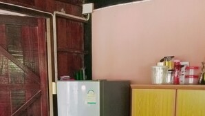 A kitchen with a refrigerator, wooden cabinets, and a tiled floor. - Koh Chang Garden Lodge Guest  Room G (Klong Son)