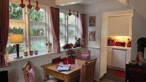 Un comedor acogedor con una mesa de madera, sillas y una ventana con cortinas.