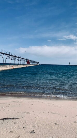 Um cais que se estende até o mar, com um farol ao longe.