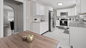 Una cocina moderna con armarios blancos, electrodomésticos de acero inoxidable y una mesa de comedor de madera.