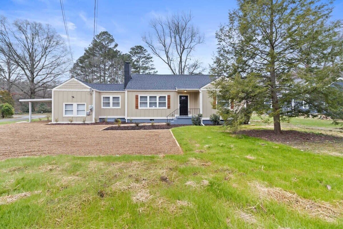A single-story house with a front porch, a chimney, and a well-maintained lawn.