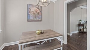 Un comedor con mesa de madera y banco, un cuadro en la pared y una lámpara de araña.