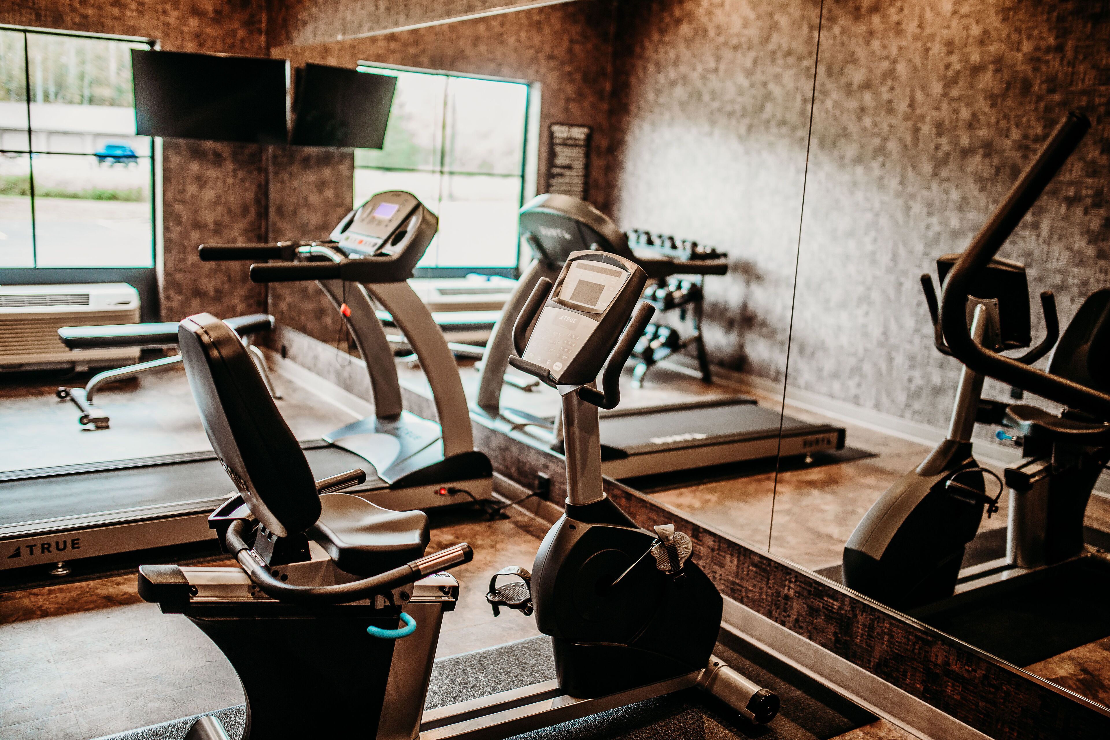 A gym with exercise equipment including treadmills, stationary bikes, and a rowing machine.