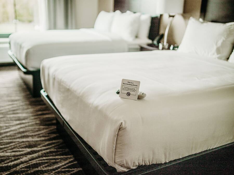 Une chambre d’hôtel avec deux lits, un panneau indiquant qu’il s’agit d’une chambre non-fumeur et un sol recouvert de moquette.