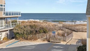 Ein Anwesen direkt am Strand mit Holzzaun, Parkplatz und Meerblick.