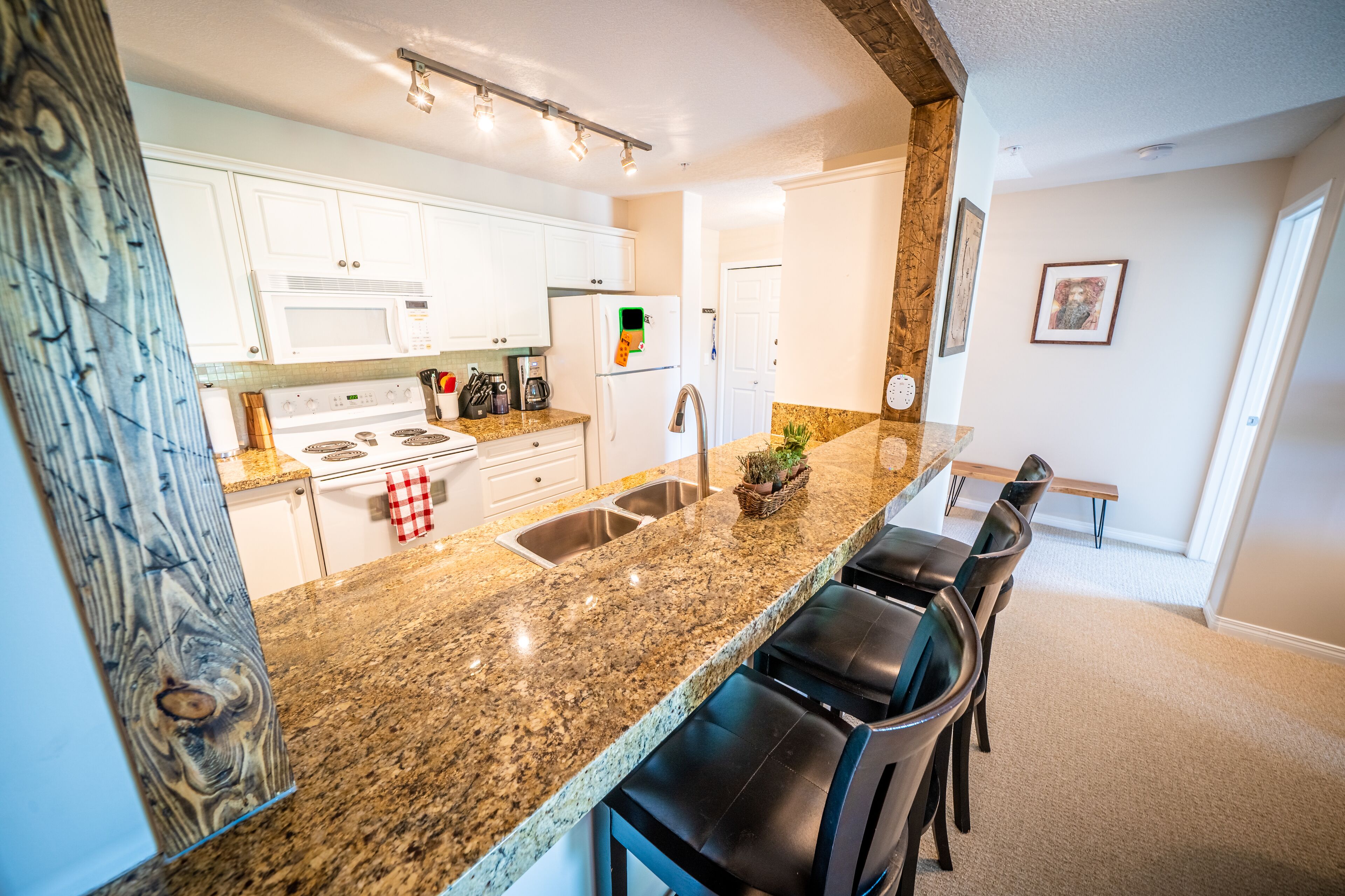 A modern kitchen with white cabinets, a granite countertop, a built-in stove, and a stainless steel sink.