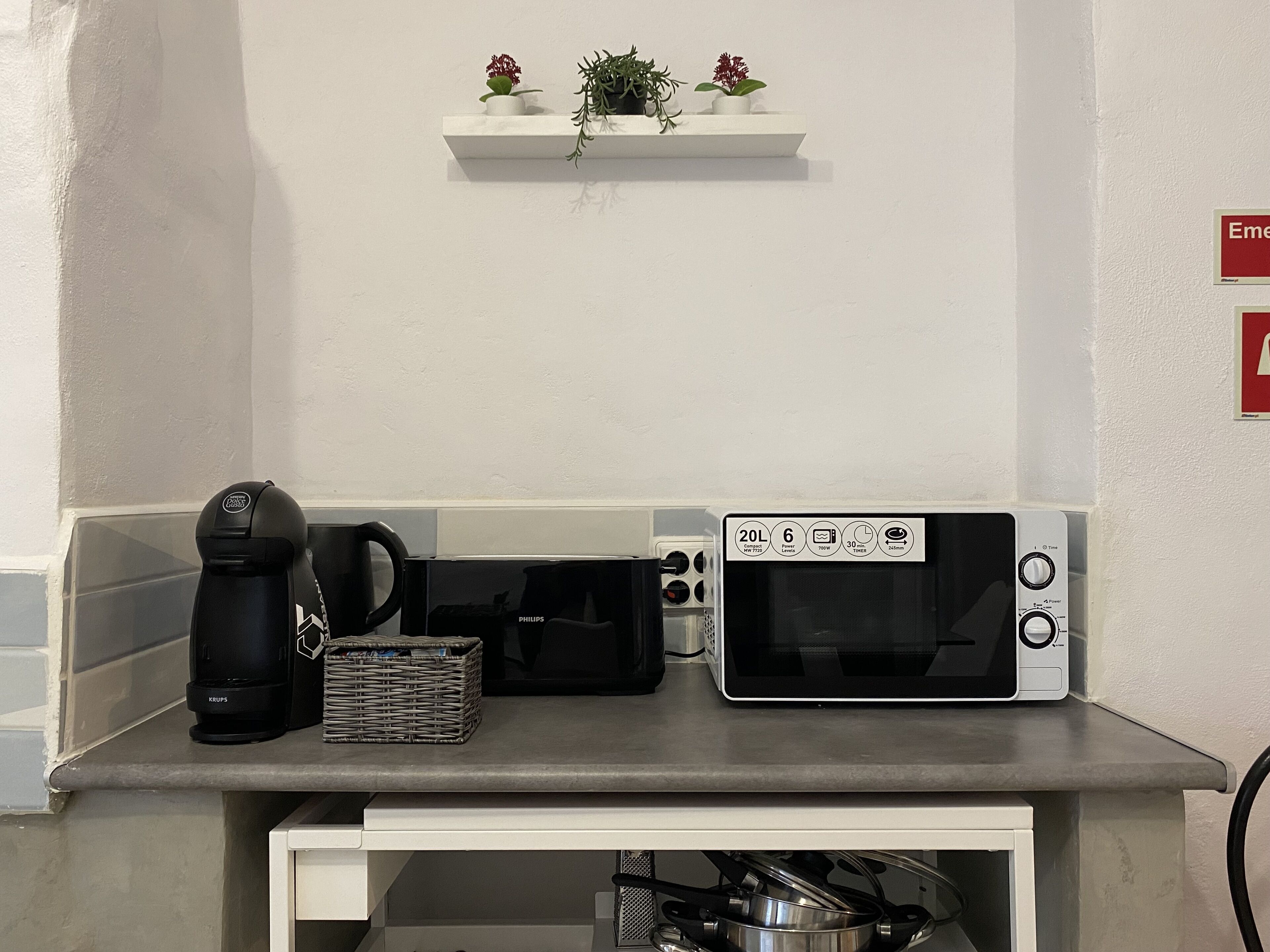 A kitchen counter with a coffee maker, microwave, and a basket.