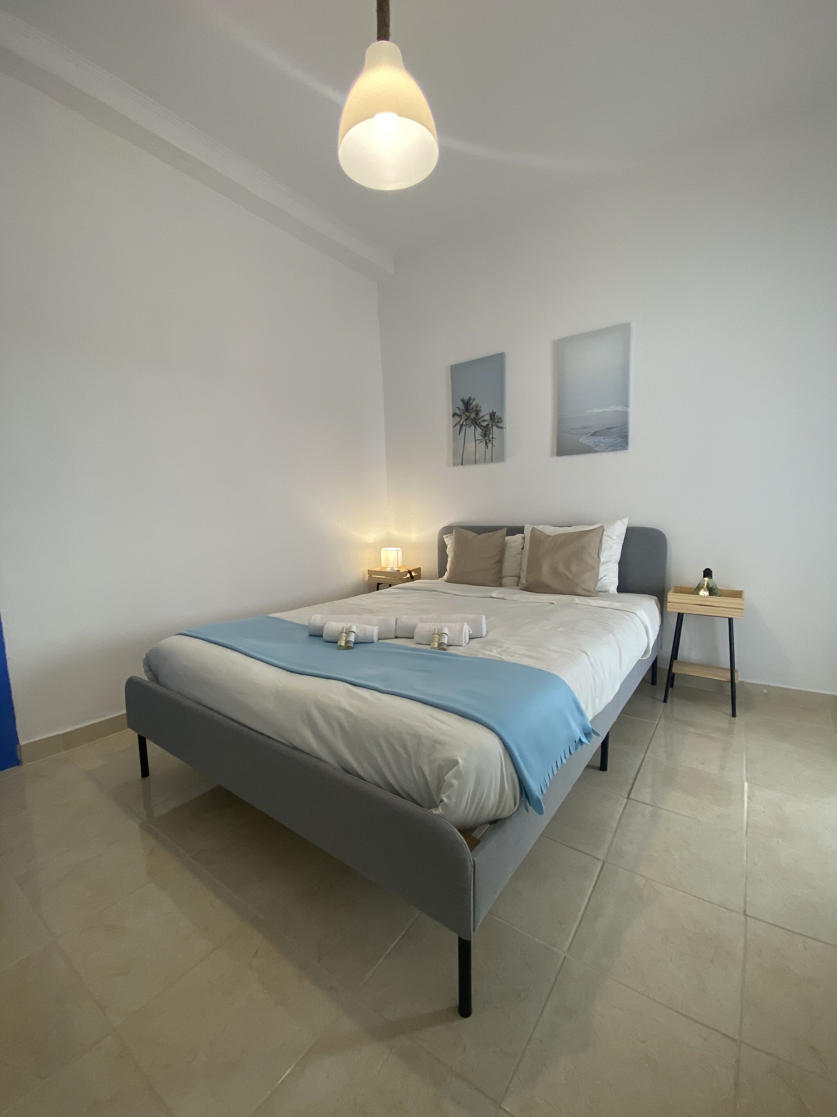 Ein modernes Schlafzimmer mit einem Bett, Nachttischen und Kunstwerken an den Wänden.
