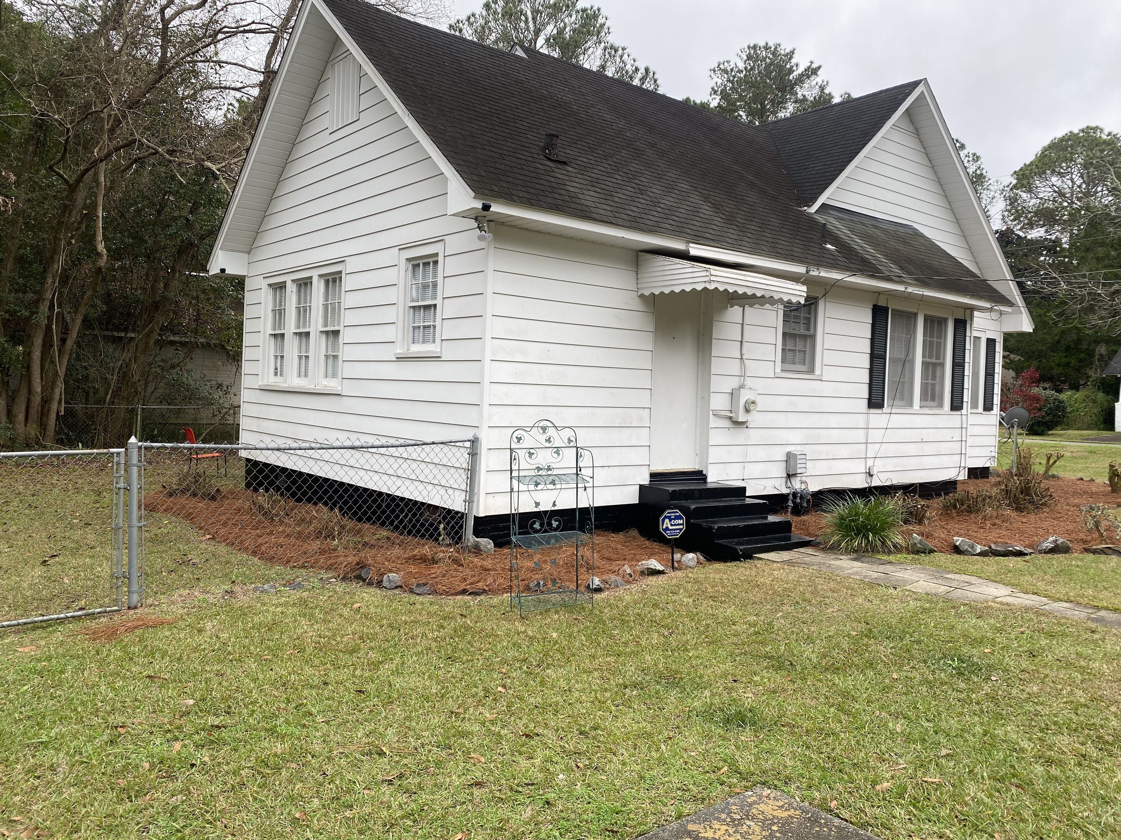 A white two-story house with a front porch, a small front yard, and a mailbox.