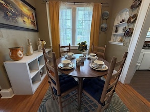 A dining area with a round table set for four, surrounded by wooden chairs.