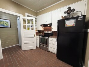 Una cocina con armarios blancos, un refrigerador negro, una estufa y un microondas.