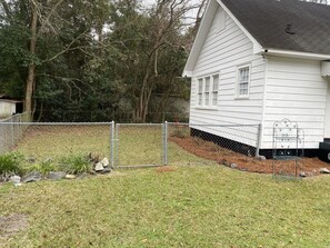 A white house with a fenced yard, surrounded by trees. - Spacious 4BR  Sleeps 12+ VSU, SGMC + Parking (Valdosta)