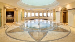 A circular hot tub with a central pole, surrounded by a tiled floor with a geometric pattern.
