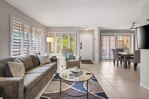 Un amplio salón con sofá, sillón y mesa de centro. Hay un comedor con mesa y sillas.
