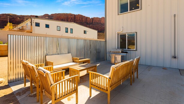 Un patio con mobiliario de madera, una parrilla y vistas a formaciones rocosas rojas.