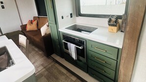 Cocina compacta con horno integrado, pileta y ventana sobre la encimera.