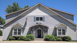 A two-story house with a stone archway entrance, a gabled roof, and a symmetrical facade. - The Inn of Lake George (Lake George)