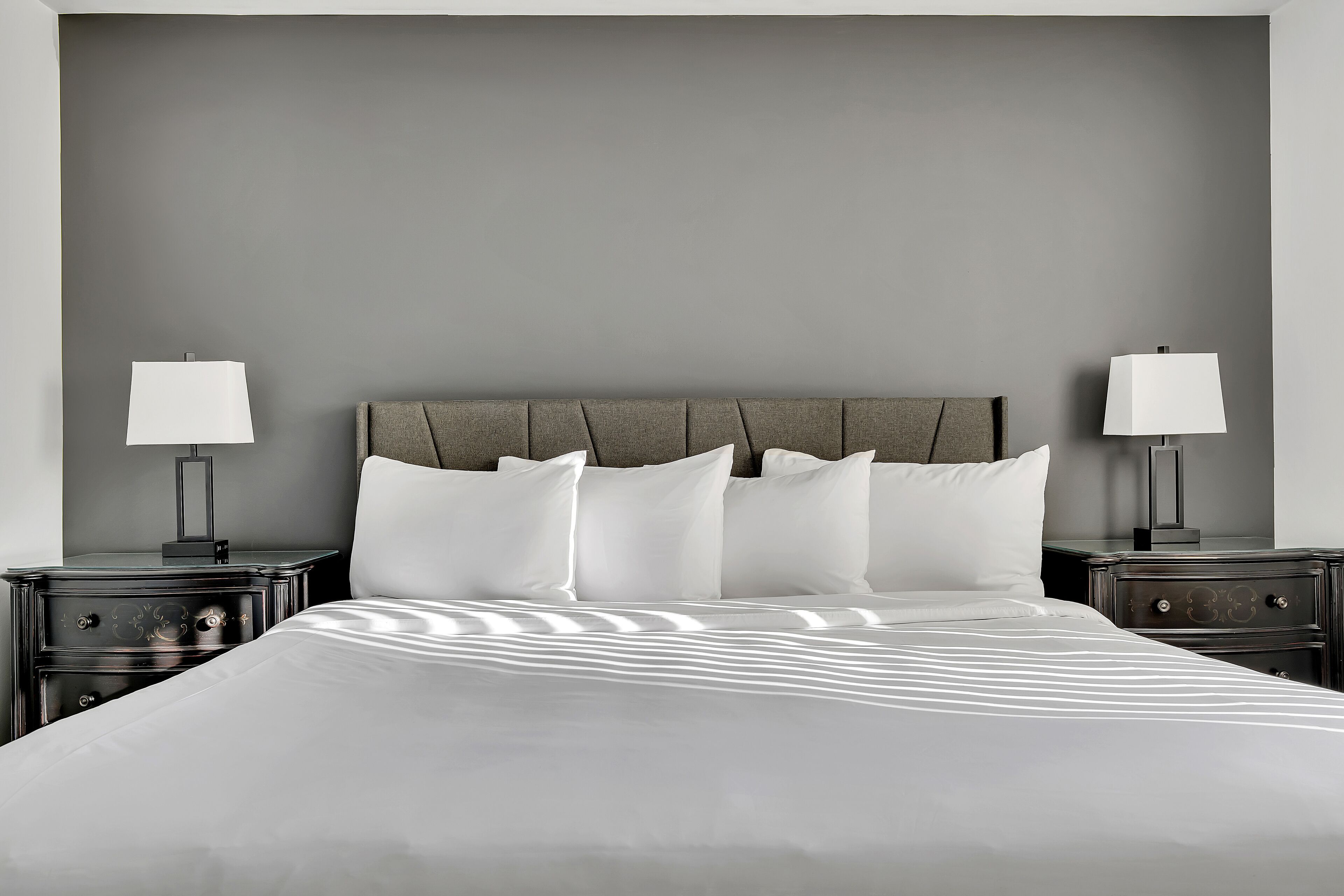 Ein modernes Hotelzimmer mit einem großen Bett, zwei Nachttischen mit Lampen und einer neutralen Farbgestaltung.
