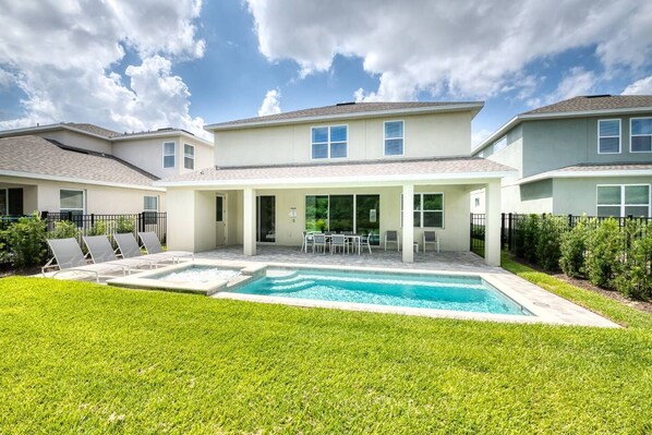 A modern two-story house with a swimming pool, a covered patio, and a well-maintained lawn.