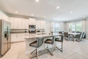 A modern kitchen with white cabinets, stainless steel appliances, and a granite countertop. - Shining Villa with Home Theater at Encore (Kissimmee)