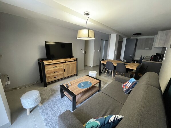 Un salon moderne comprenant un canapé, une table basse, un téléviseur et un coin repas.