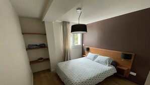 A bedroom with a bed, a nightstand, a lamp, a shelf with a plant, and a window with curtains. - ARC 1800 apartment 6-8pers with garage all comfort (Bourg-Saint-Maurice)