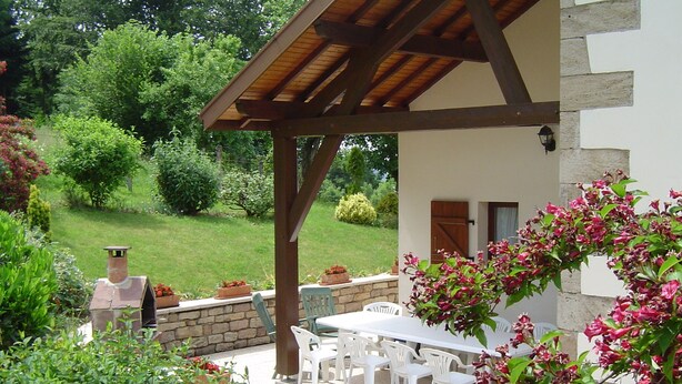 A covered patio with a table and chairs, surrounded by potted plants and a stone wall. - Combeauté valley 2 to 10pers. (Le Val-d'Ajol)