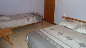 A bedroom with two single beds, a wooden door, and a small bedside table with a lamp. - Combeauté valley 2 to 10pers. (Le Val-d'Ajol)
