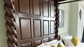 A hotel room with a wooden headboard, two beds with white and yellow pillows, and a wooden nightstand.