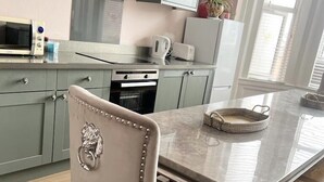 A kitchen with light grey cabinets, a stainless steel range hood, a microwave, and a stove.
