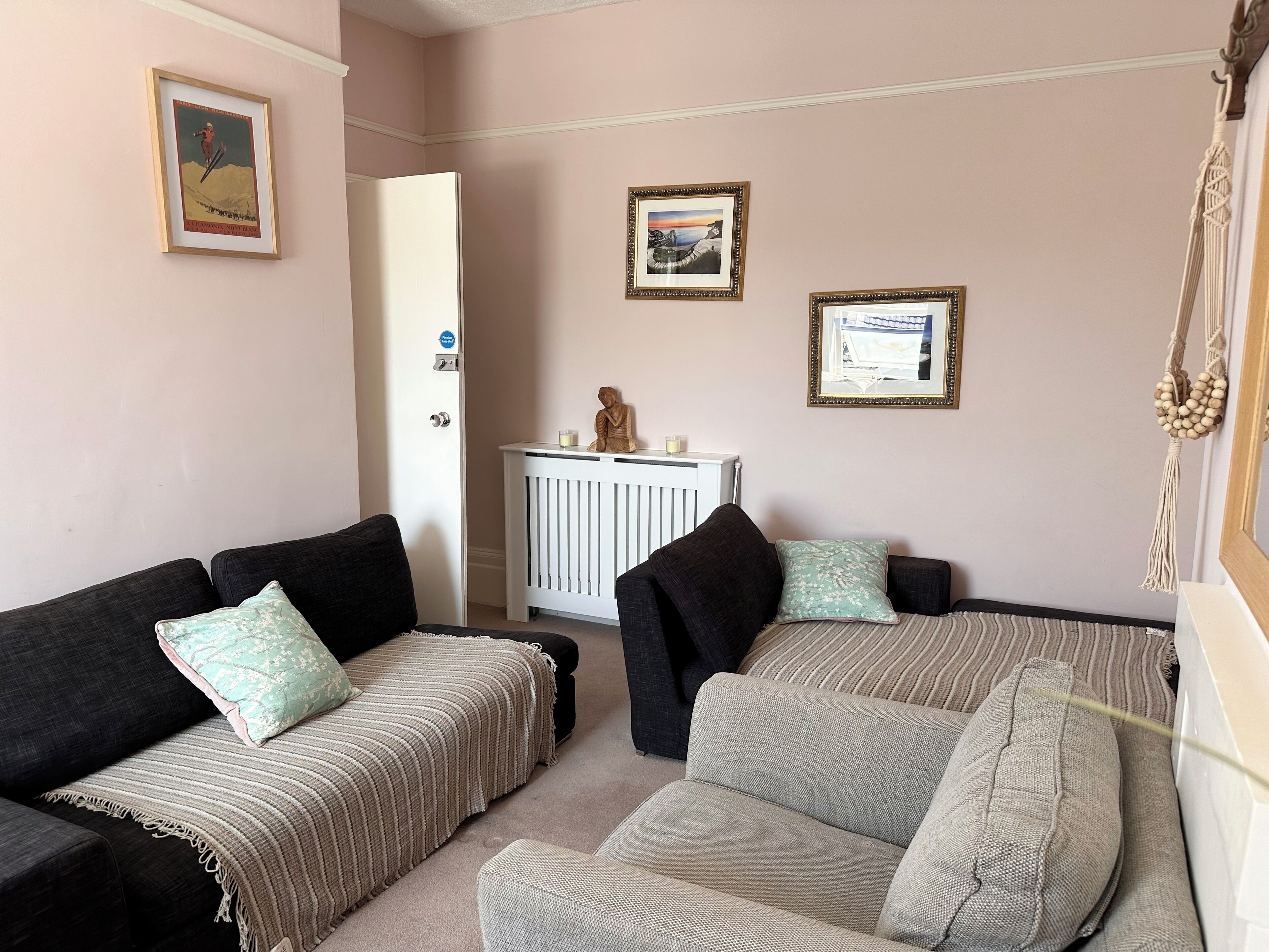 A living room with two sofas, a radiator, and framed pictures on the wall.
